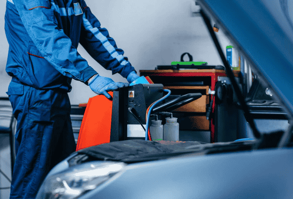 Technician performing a car air conditioning installation using specialised equipment.