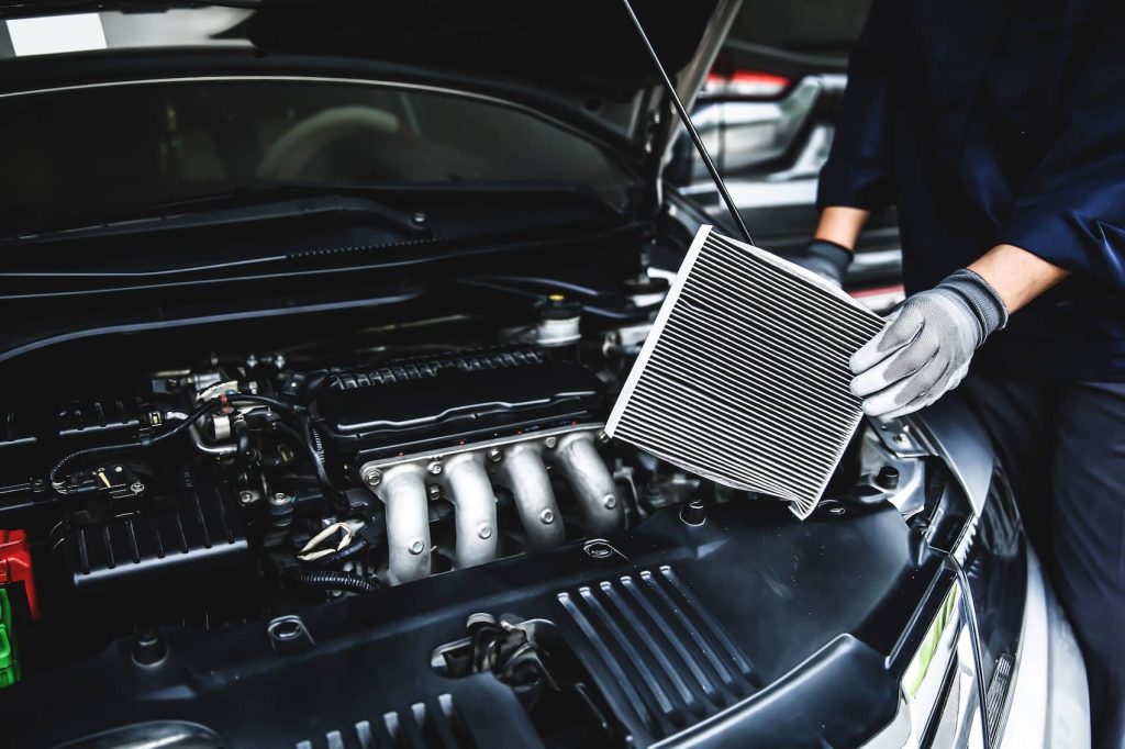 Technician replacing a car’s cabin air filter during an aircon repair service.