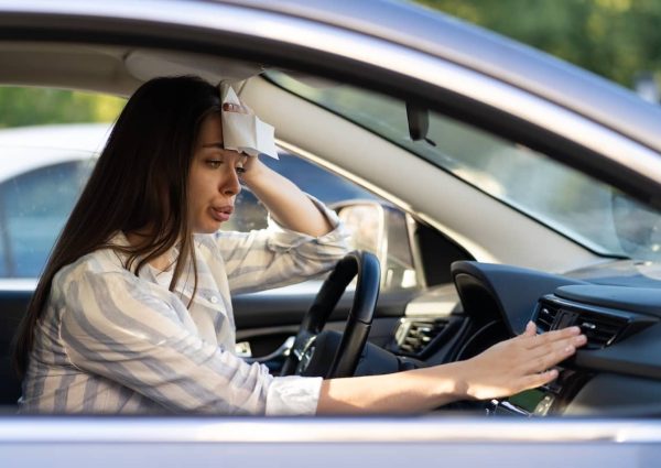 Frustrated woman in a hot car trying to fix her broken air conditioning system.